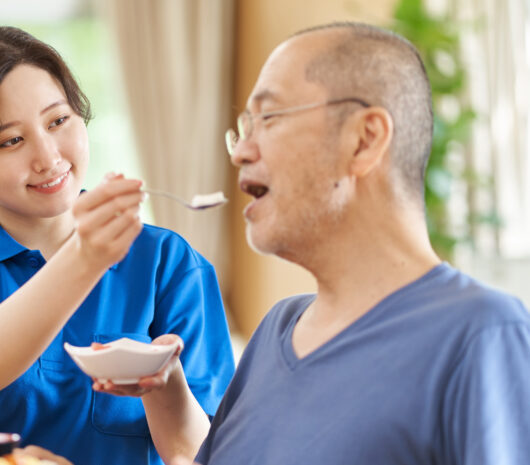 高齢者に食事の介助をする介護士